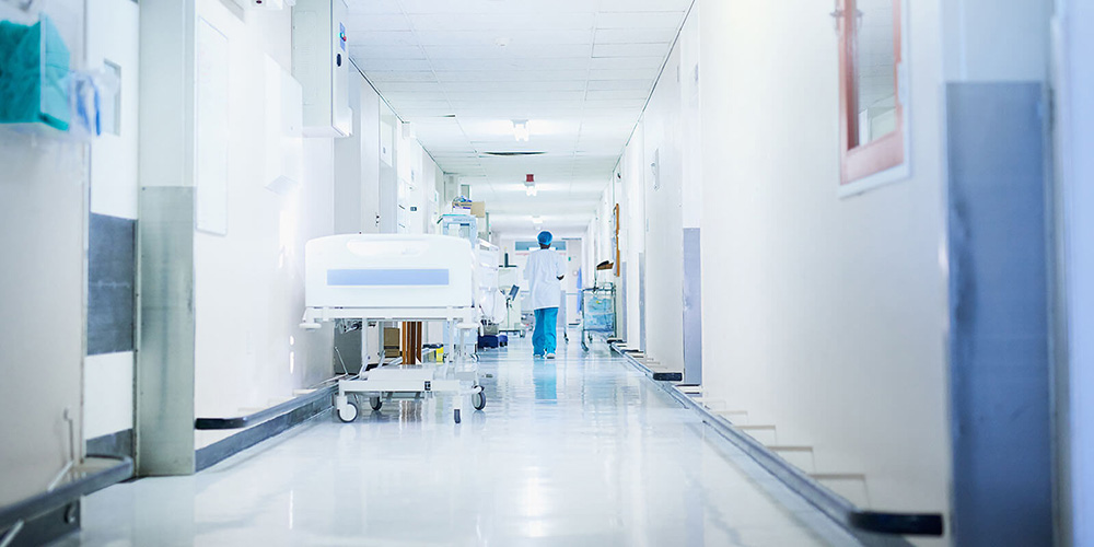 Image of a doctor walking down an empty hospital corridor