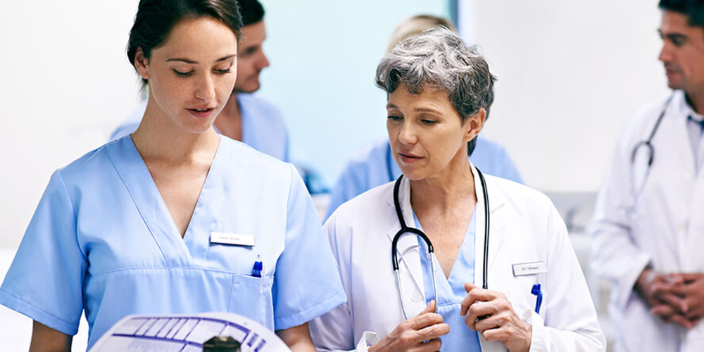 Doctors & nurses smiling and chatting in a busy hospital hallway, showcasing teamwork and care in a healthcare setting.