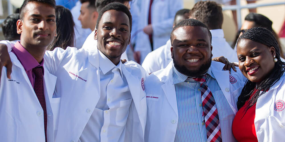A group of SGU students gathers after receiving their white coats