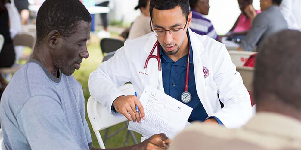 A small group of SGU students volunteer their time conducting physical exams during an outdoor clinic.|Skip the Med School Waitlist. Episode 1: 4 Perks of attending an international medical school.