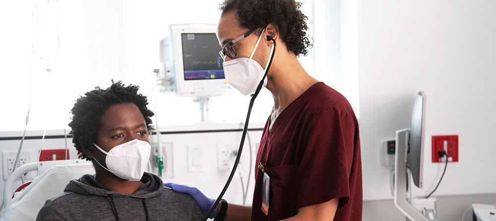 Internist examining patient in hospital bed