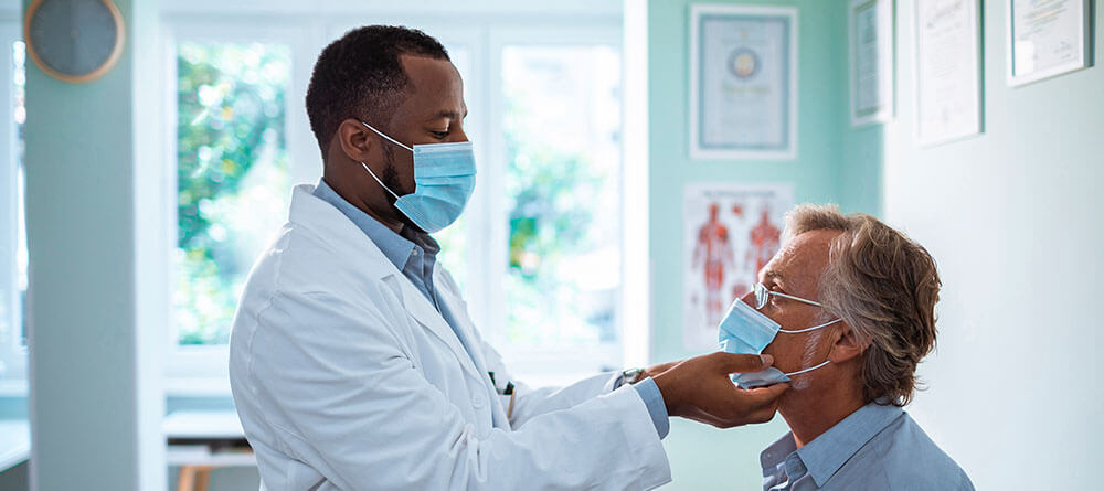 A doctor carefully examines an older man during a routine check-up in a bright, welcoming clinic.