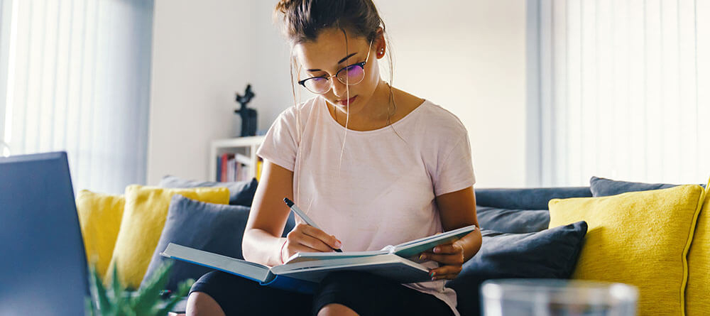 Female student sitting on couch preparing medical school application materials.