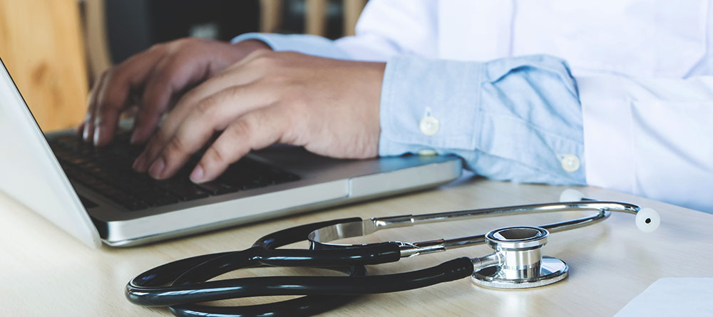 A person focused on typing on a laptop, fingers flying over the keyboard in a cozy workspace.