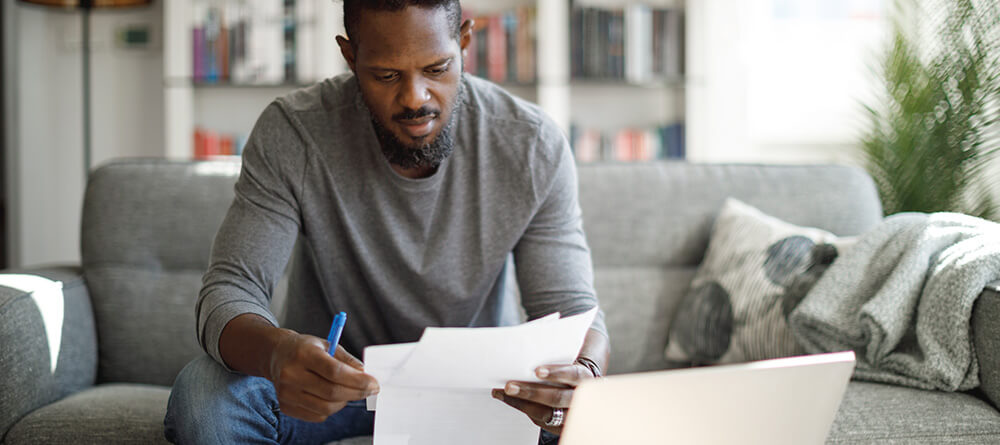 Man sitting on couch reviewing his medical school application materials