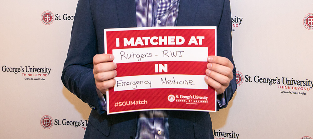 Student holding match sign