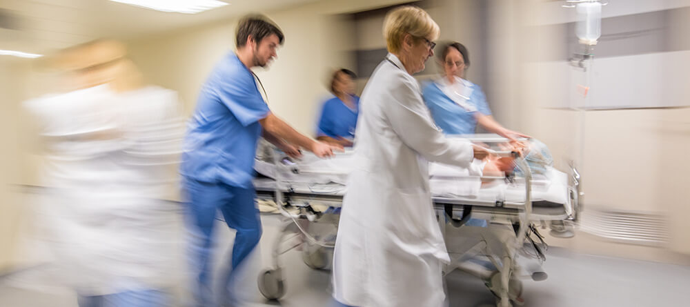  Image of hospital staff quickly ushering a patient off for treatment.