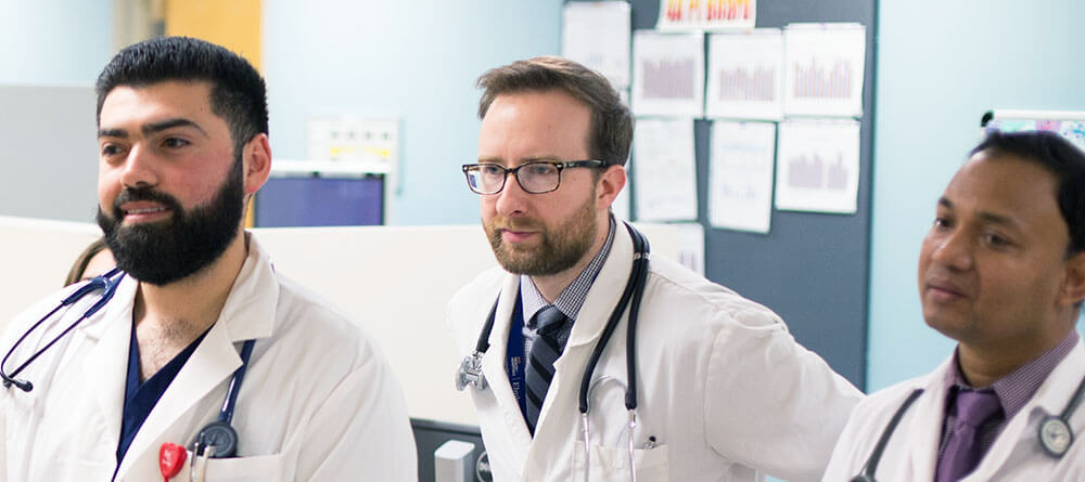 A group of physicians share a moment as they read an update.
