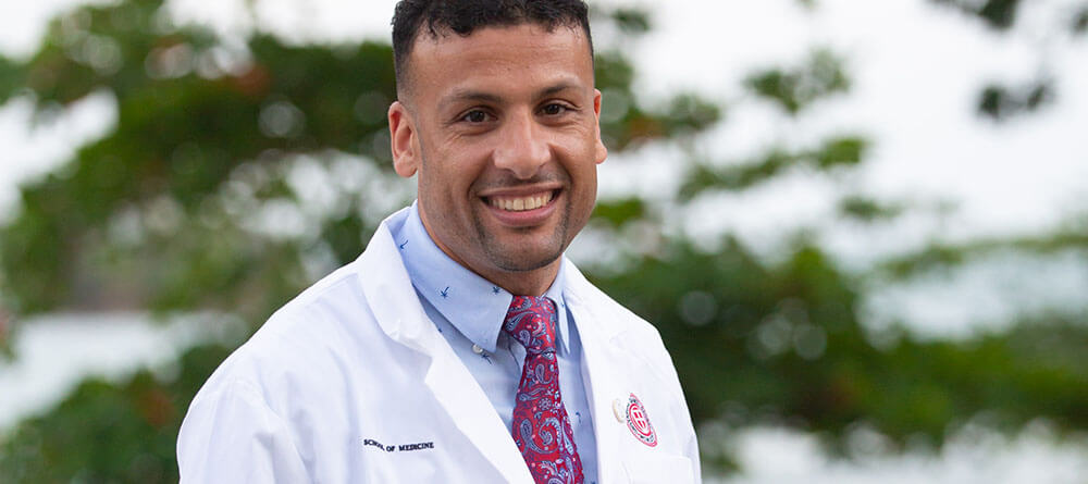 An SGU student smiles as they wear their white coat, which is a symbol of the transition to life as a doctor.