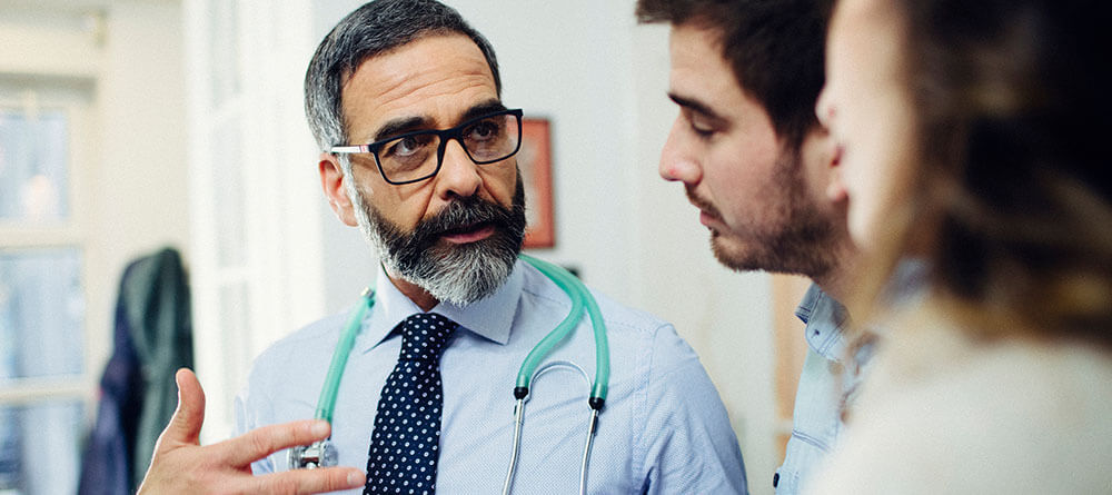  A family physician discusses a diagnosis with a young couple.