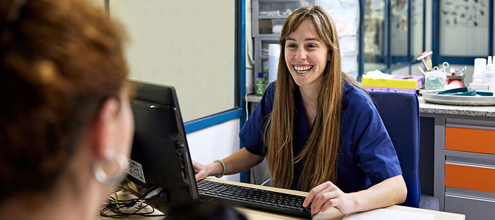 A pre-vet student smiles while interacting with a client in a veterinary clinic.