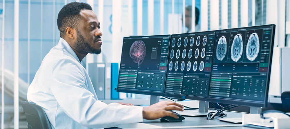 Male neurologist examines diagnostic image results on computer.