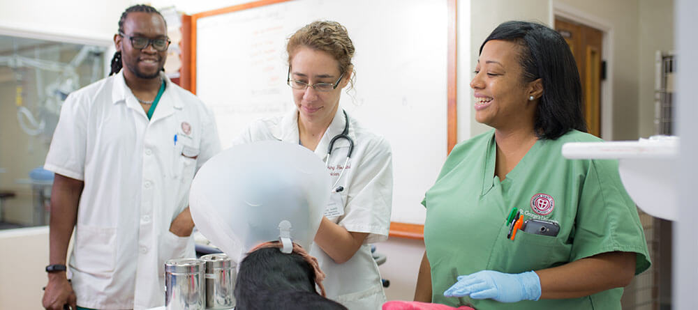 SGU instructor overseeing two veterinary students treating a dog