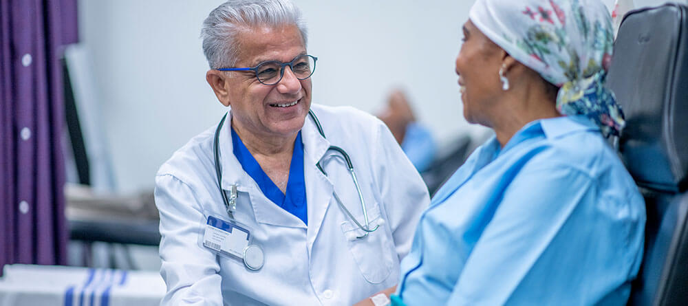A doctor smiles while speaking with a patient during a hospital visit