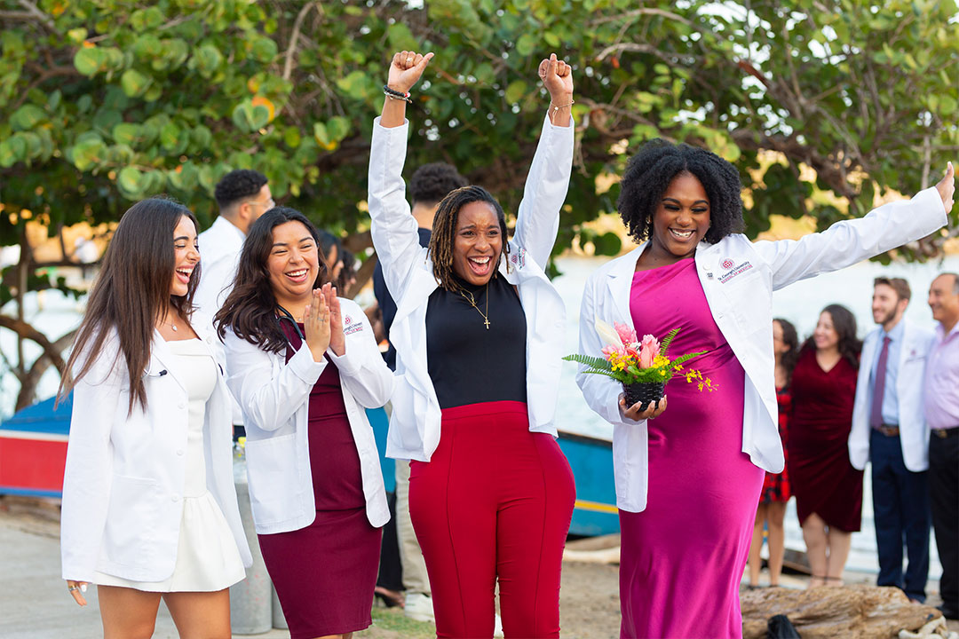 Four students in white coats celebrating