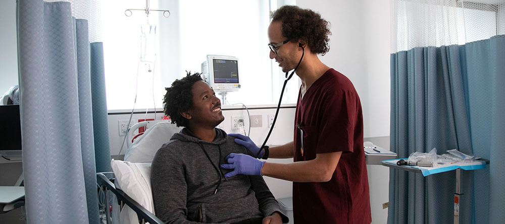 A medical student examines a patient in a lab setting at SGU.