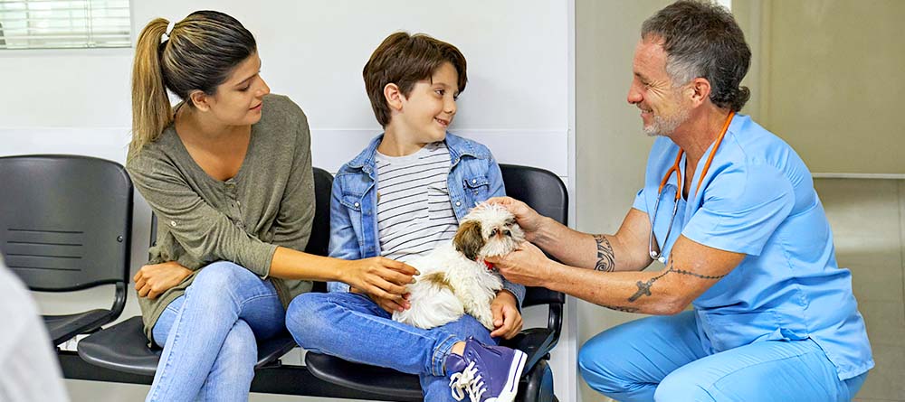 Veterinarian speaking with young boy and his mom with dog in waiting room