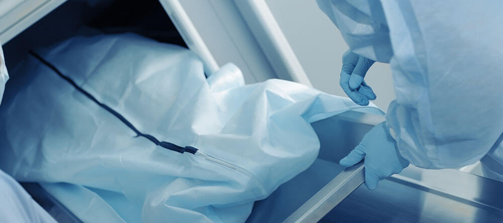 A forensic pathologist prepares to ready a body for autopsy