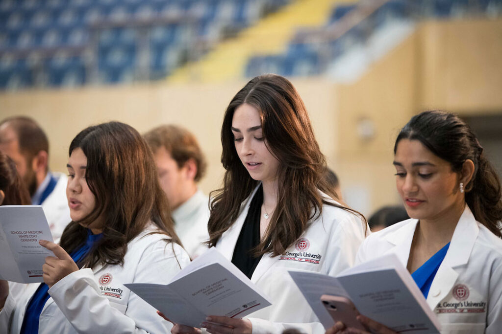 Students reading the White Coat Ceremony program