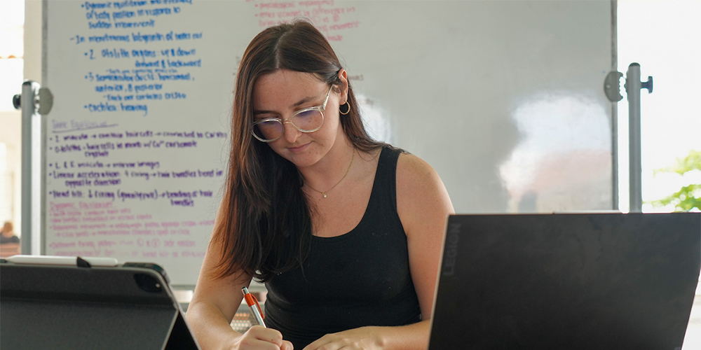 A female student is engaged in writing notes as she studies for the MCAT exam.